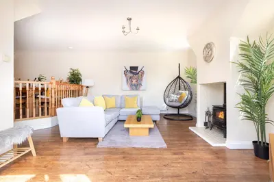 a living room with a white couch and a fireplace at JOIVY Greenknowes Cottage with Hot Tub & Fireplace in Kelty