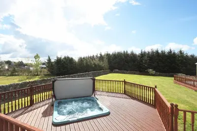 a hot tub sitting on a wooden deck at JOIVY Greenknowes Estate with Hot Tub and Bar - Farmhouse and Lodge in Kelty