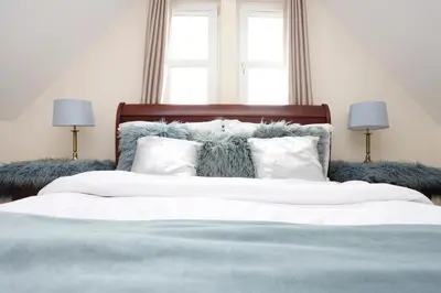 a bedroom with a bed with white sheets and pillows at JOIVY Greenknowes Estate with Hot Tub and Bar - Farmhouse and Lodge in Kelty