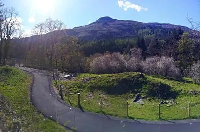 a winding road with a mountain in the background at An Carraig Log Cabin in Strathyre