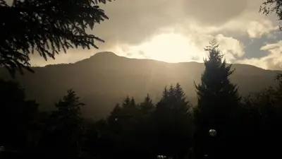 a view of a mountain with the sun shining on it at An Carraig Log Cabin in Strathyre