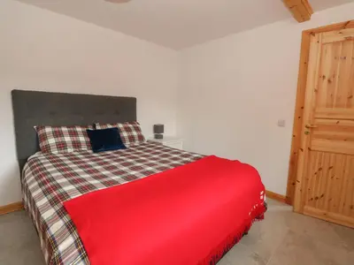 a bedroom with a red bed and a wooden door at Bradan Lodge in Dalmally