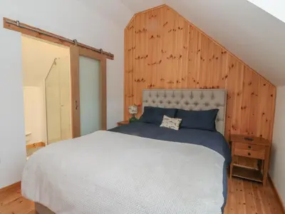a bedroom with a large bed with a wooden wall at Bradan Lodge in Dalmally