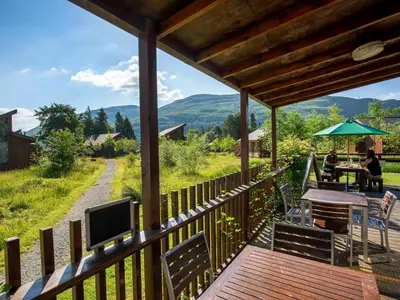 a wooden deck with a table and a tv on top at Ardgartan Argyll Cabins - Forest Holidays in Arrochar
