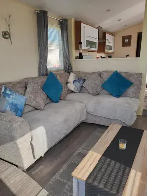 a living room with a gray couch with blue pillows at B&R 18 Gleneagles in Turnberry
