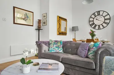 a living room with a couch and a clock on the wall at Alloa City Centre in Alloa