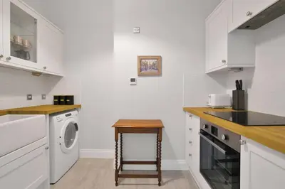 a white kitchen with a washing machine and a table at Alloa City Centre in Alloa