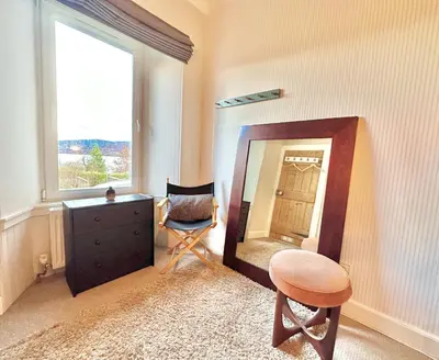 a room with a mirror and a chair and a dresser at Cherry Trees in Inveraray