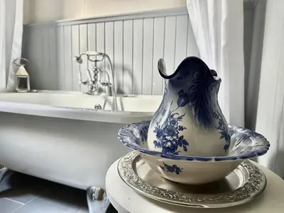 a blue and white vase on a table next to a bath tub at Cherry Trees in Inveraray