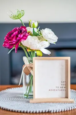 a vase of flowers and a sign on a table at Chalet Loch Leven Lodge 21 by Interhome in Kinross