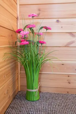 a green vase filled with pink flowers in front of a wall at Chalet Loch Leven Lodge 21 by Interhome in Kinross