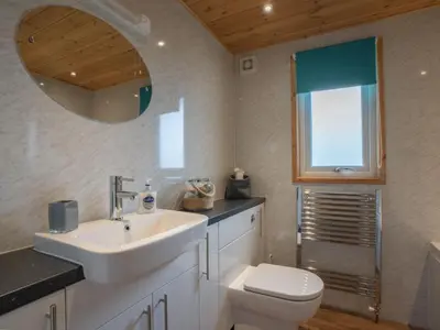 a bathroom with a sink and a toilet and a mirror at Chalet Loch Leven Lodge 21 by Interhome in Kinross