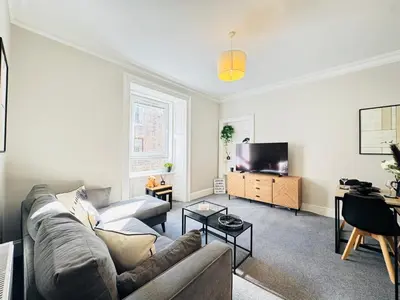 a living room with a couch and a tv at Elegant City Centre Apartment in Edinburgh
