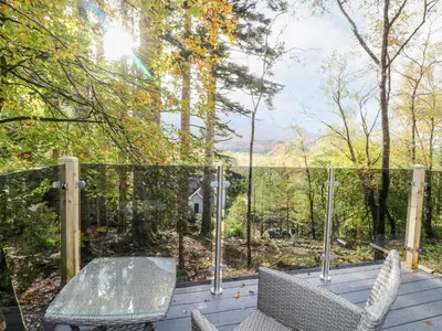 a patio with a glass table and chairs on a deck at Elleric Pods - The Last Resort in Appin