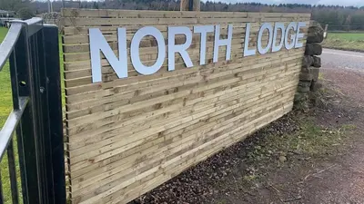 a wooden fence with a sign that reads northern lodge at North Lodge Holiday Home, Hot Tub & Sauna in Carnwath