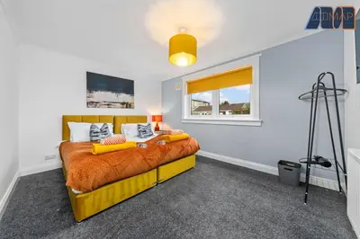 a bedroom with a yellow bed with a window at Cosy 2-Bed House I Easy Edinburgh Access I Sleeps 4 in Whitburn