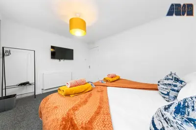 a room with a bed with yellow pillows and a tv at Cosy 2-Bed House I Easy Edinburgh Access I Sleeps 4 in Whitburn