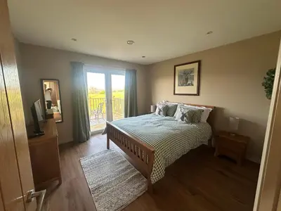 a bedroom with a bed and a sliding glass door at Ardenvhor - Loch Lomond in Gartocharn
