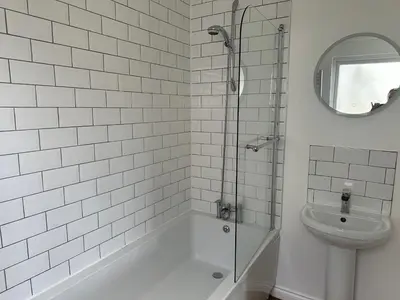 a white tiled bathroom with a shower and a toilet at Ardenvhor - Loch Lomond in Gartocharn