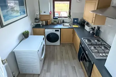 a small kitchen with a washing machine and a stove at Cosy stylish Duntocher flat near Glasgow in Clydebank