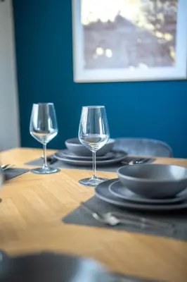 a table with two wine glasses and plates on it at 2 BDR House By Caledonia Luxe Stays Short Lets & Serviced Accommodation Bathgate in Bathgate