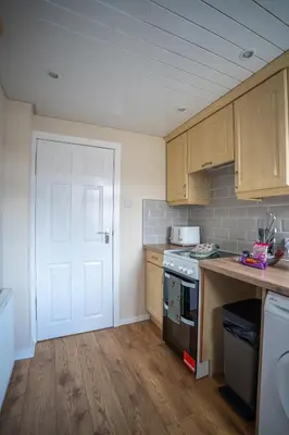 a kitchen with wooden cabinets and a white door at 2 BDR House By Caledonia Luxe Stays Short Lets & Serviced Accommodation Bathgate in Bathgate