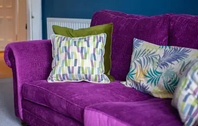 a purple couch with three pillows on it at Newly Renovated Flat in Trendy Finnieston in Glasgow