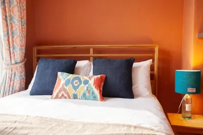 a bed with two pillows and a blue lamp on a table at Newly Renovated Flat in Trendy Finnieston in Glasgow