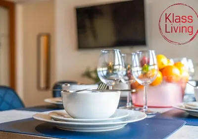 a table with a bowl and plates and wine glasses at Oxford Apartment by Klass Living in Coatbridge