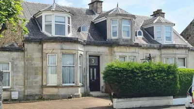 an old stone house with a black door at 5 Bedrooms Sleeps 10 Full Kitchen Parking in Ayr