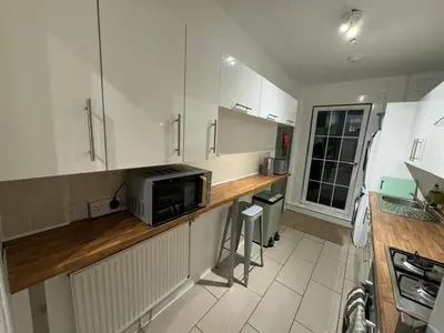 a kitchen with white cabinets and a microwave on a counter at Stirling Haven: Charming 3B Apt in City Centre in Stirling