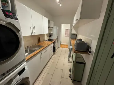 a kitchen with white cabinets and a sink and a microwave at Stirling Haven: Charming 3B Apt in City Centre in Stirling