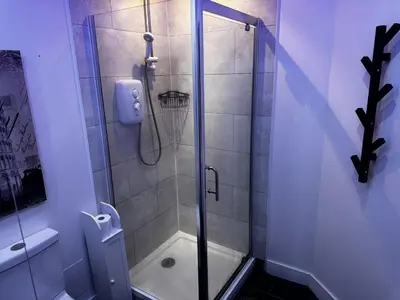 a shower with a glass door in a bathroom at Modern 3-Bedroom Home with Cozy Cinema-Style Living Space in Cumbernauld