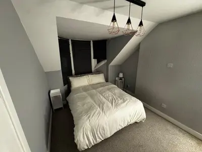 a bedroom with a white bed in a attic at Modern 3-Bedroom Home with Cozy Cinema-Style Living Space in Cumbernauld