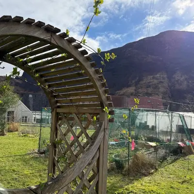 a wooden gate in a field with a mountain in the background at Mountain View House Kinlochleven in Kinlochleven