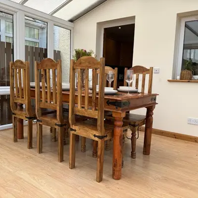 a wooden dining room table with chairs and wine glasses at Mountain View House Kinlochleven in Kinlochleven