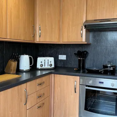 a kitchen with wooden cabinets and a stove top oven at Mountain View House Kinlochleven in Kinlochleven