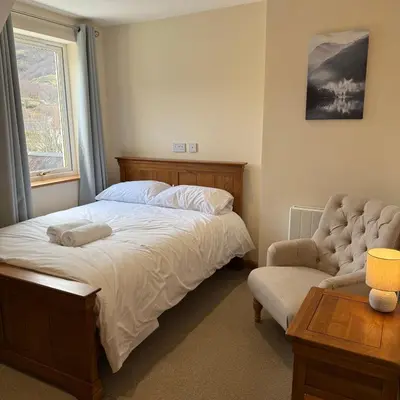 a bedroom with a bed and a chair and a window at Mountain View House Kinlochleven in Kinlochleven