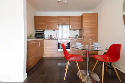 a kitchen with a table and two red chairs at Argyle Apartment in Glasgow