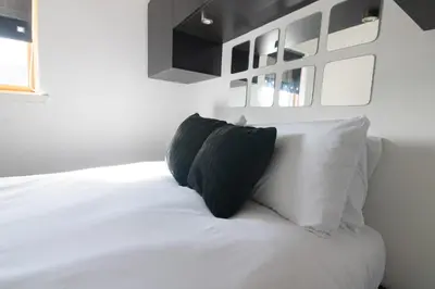 a white bed with two black pillows on it at Argyle Apartment in Glasgow