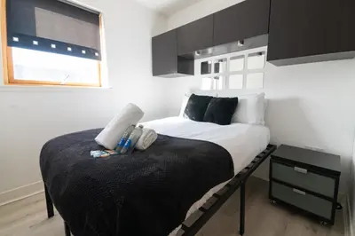a small bedroom with a bed with a black blanket at Argyle Apartment in Glasgow