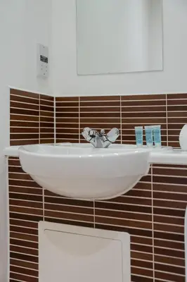 a bathroom with a white sink on a brown tiled wall at Argyle Place in Glasgow