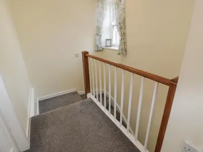a staircase with a wooden rail and a window at Morton Mains Steading Cottage in Thornhill