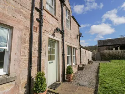 an old brick house with a white door at Morton Mains Steading Cottage in Thornhill
