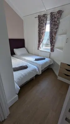 two beds in a room with a window at The Dochart Lodge with hot tub Braidhaugh Crieff in Crieff