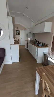 a large kitchen with white cabinets and a table at The Dochart Lodge with hot tub Braidhaugh Crieff in Crieff