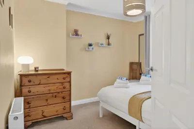 a bedroom with a bed and a dresser in it at The Bruadair - Modern Town Living in Ardrossan