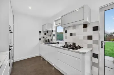 a white kitchen with a sink and a stove at The Bruadair - Modern Town Living in Ardrossan