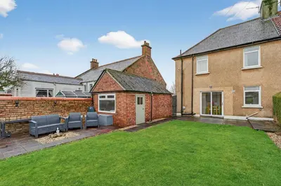 a backyard of a brick house with a lawn at The Bruadair - Modern Town Living in Ardrossan