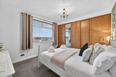 a bedroom with a large white bed with a window at The Bruadair - Modern Town Living in Ardrossan